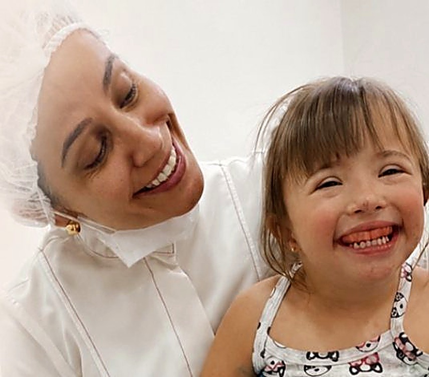 Patrícia sorrindo com uma paciente no colo